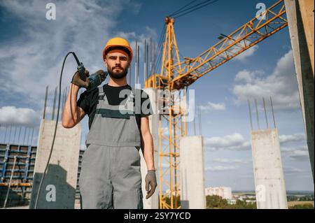 Portrait of man that is in uniform with the drill on the construction site. Stock Photo