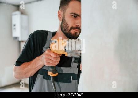 Drilling the hole in wall. The man is making repairs in the apartment. Stock Photo