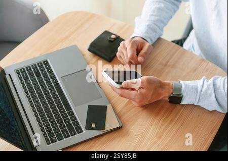 Close up view of man that sitting by the table and working by using smartphone. Stock Photo