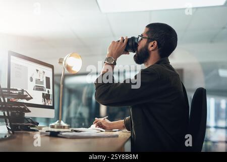 Creative man, computer and drinking with coffee at night for overtime, project deadline or caffeine at office. Businessman, employee or web designer Stock Photo
