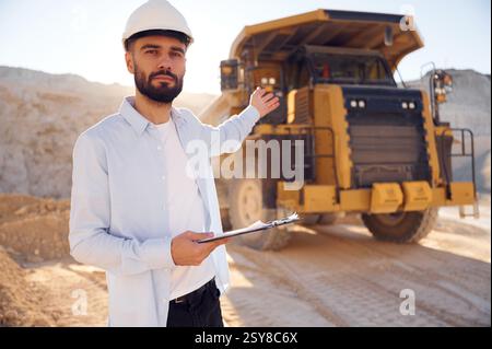 Smart person is with documents in hands. Man in uniform is working in the quarry at daytime. Stock Photo