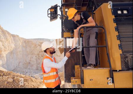 Taking the documents. Two men in uniform are working together in the quarry. Stock Photo