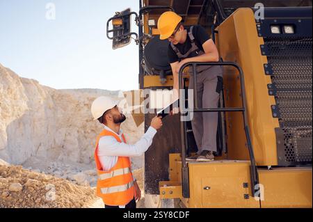 Taking the documents. Two men in uniform are working together in the quarry. Stock Photo