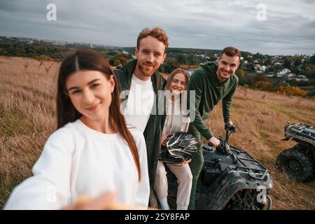 Selfie type view. Two young couples with quad bikes is together on the field. Stock Photo