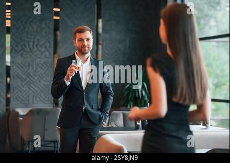 Man in suit is talking with woman that is in black dress on the party. Stock Photo