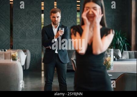 Man in black suit is angry at woman that is standing and crying. Stock Photo