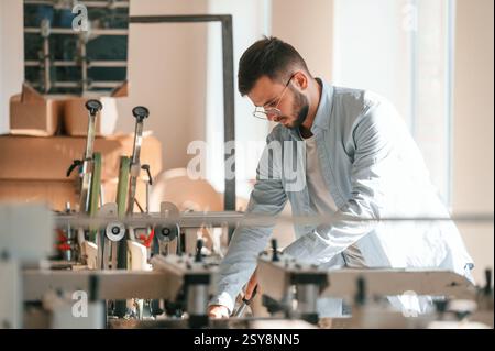 Modern printing machine. Typography worker in white clothes is indoors. Stock Photo