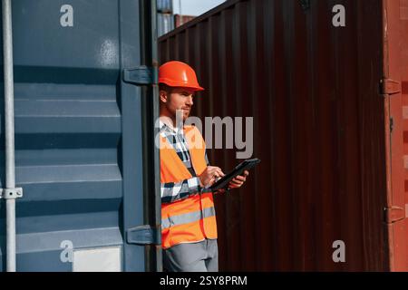 Male worker is on the location with containers. Using digital tablet. Stock Photo