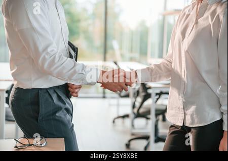Doing handshake. Man and woman are working in the modern office together. Stock Photo