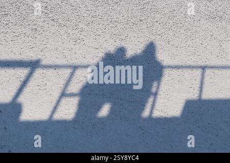 The shadows of a man and a woman are visible on the snow. Stock Photo