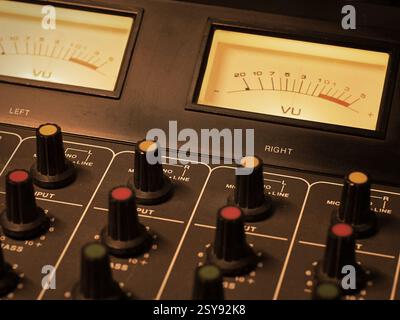 Detail of an analog studio mixer. Professional audio console with illuminated VU meters and knobs. Ideal for sound engineering, music production Stock Photo