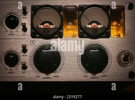 Detail of an analog studio equipment. Professional audio preamp with illuminated vacuum tubes, knobs, and faders, ideal for sound engineering and musi Stock Photo