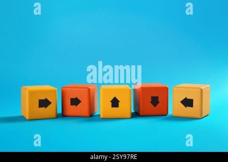 Colorful cubes with arrows pointing in different directions on light blue background Stock Photo