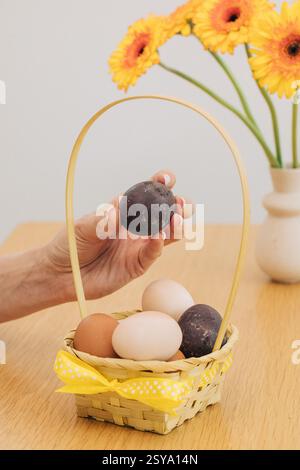 A woman holds an Easter egg over a wicker basket. Happy Easter. Stock Photo