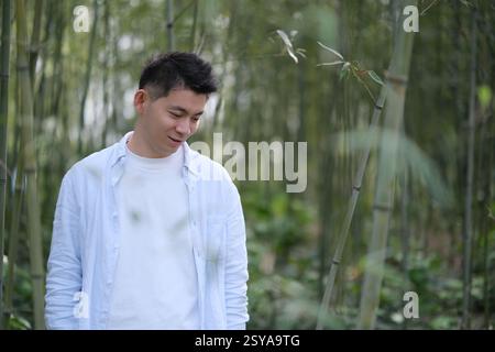Asian young man at bamboo grove, looking down Stock Photo