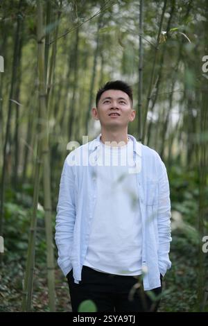 Asian young man at bamboo grove, looking up Stock Photo