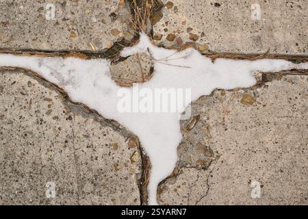 Snow in pavement cracks closeup abstract Winter weather climate change. Stock Photo