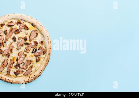 Top view of a gourmet pizza topped with sous-vide duck fillet, figs, almonds, and truffle sauce, beautifully presented on a pastel blue background, ad Stock Photo