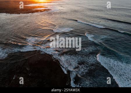 Stunning aerial shot capturing the golden sunset over the waves and rocky landscape of Popcorn Beach, Fuerteventura Stock Photo