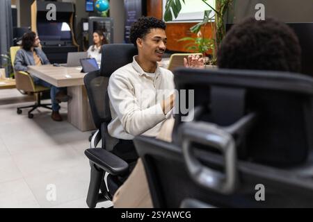 A modern office setting with colleagues engaging in conversation. Comfortable seating and plants create a relaxed atmosphere, fostering collaboration Stock Photo