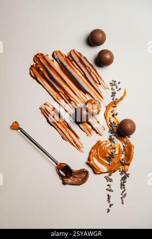 Chocolate balls on a cream surface. A decorative swirl of caramel adds a sweet touch, with cocoa nibs scattered, creating a delightful visual treat. Stock Photo
