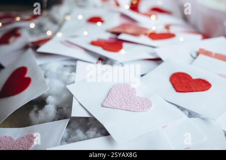 A collection of handmade Valentine's Day cards with red hearts on white envelopes, scattered decoratively. Perfect for expressing love and affection. Stock Photo