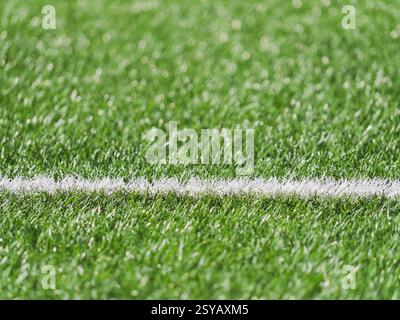 A close up image showcasing the lush green grass of a soccer field with a crisp white line marking. The vibrant texture highlights the field well main Stock Photo