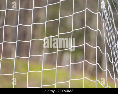 Close up image of a soccer goal net with a blurred background, depicting an outdoor soccer setting. The net is white, enhancing the theme of textures. Stock Photo
