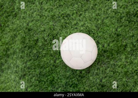 A centered soccer ball rests on a vibrant green grass field, showcasing its classic black and white design. The image highlights soccer, textures and Stock Photo