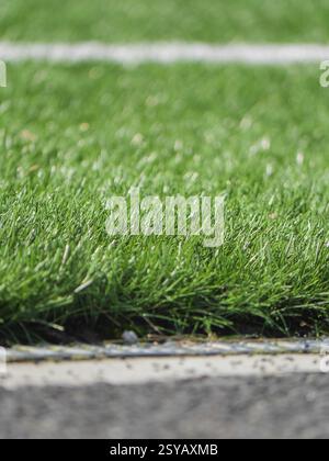 A close up image of vibrant artificial grass with a white line, depicting a section of a synthetic soccer field. The textured surface showcases detail Stock Photo