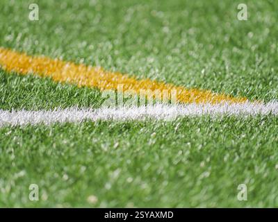 A detailed close up of white and yellow lines on vibrant green artificial turf. Perfect for illustrating soccer related themes or concepts of textures Stock Photo