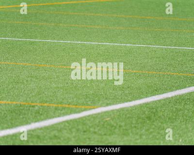A close up view of a green artificial turf soccer field, featuring vibrant white and yellow lines intersecting diagonally, ideal for backgrounds or so Stock Photo