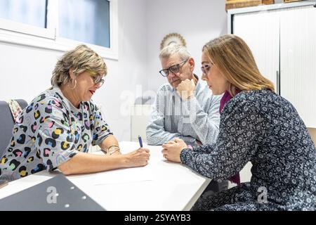 A couple with intellectual disabilities engaged in a focused supervision meeting. They are discussing documents, communication, and collaboration in a Stock Photo
