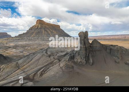 A breathtaking landscape featuring a towering desert mesa and striking rock formations under a vivid blue sky with scattered clouds in Hanskville, Uta Stock Photo