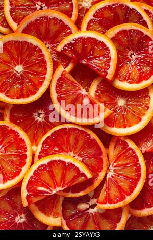 A close-up view of freshly sliced blood oranges revealing vibrant red and orange hues. The juicy segments create a pattern, highlighting natural beaut Stock Photo