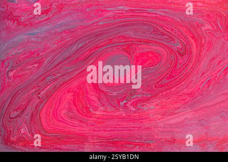 A striking abstract art piece featuring acrylic paint pink and red swirls. This fluid acrylic painting creates a sense of movement and energy, perfect Stock Photo