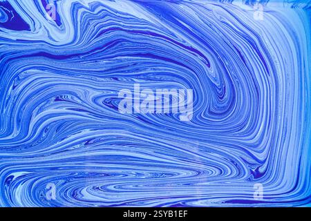 This image showcases a pattern of blue and white acrylic paint swirls resembling marble. The fluid, abstract design creates a sense of motion and eleg Stock Photo