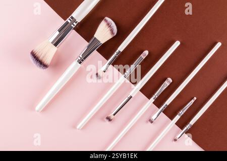 Elegant arrangement of various makeup brushes on a two toned pink and brown background. Perfect for beauty and cosmetics content, highlighting style a Stock Photo