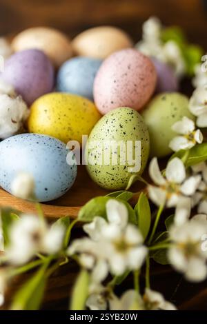 Pastel-colored Easter eggs rest alongside delicate white blossoms, creating a charming and festive display perfect for spring celebrations and decorat Stock Photo