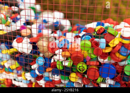 A vibrant assortment of plastic bottle caps collected in a basket, emphasizing the importance of recycling to reduce plastic waste. Stock Photo