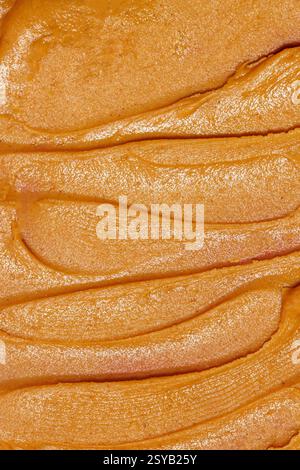 A close-up image showcasing the smooth, creamy texture of freshly spread peanut butter with distinctive, even lines across the surface. Stock Photo