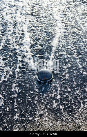 Close-up of water splash on a dark surface with bubbles and foam. The reflection adds a unique texture and dynamic effect. Stock Photo