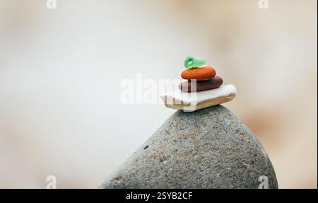 Close-up of balanced stones and glass in a tranquil setting, with a focus on various sizes and textures of rocks stacked on top of each other. Stock Photo