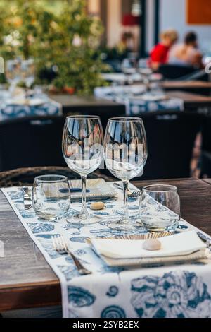 Set of glasses with white wine and plates placed on table with tablecloth on table Stock Photo