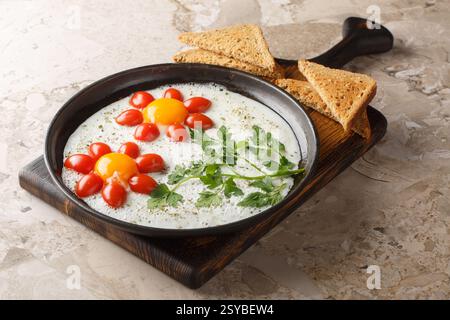 Children's food idea in the form of a flower of fried eggs, cherry tomatoes and parsley close-up in a plate on the table. Horizontal Stock Photo