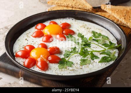 Flower shaped breakfast idea cooked fried eggs, parsley and cherry tomatoes close-up in a plate on the table. Horizontal Stock Photo