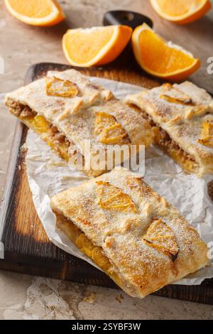 Orange strudel pie with jam, nuts, raisins and fresh fruits close-up on wooden board on table. Vertical Stock Photo