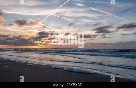 A captivating sunset featuring vibrant colors beautifully reflecting on the calm, serene ocean waters Stock Photo