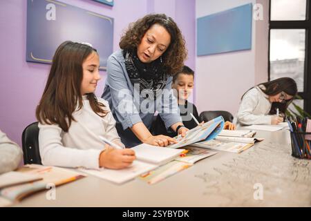 Female teacher helping elementary students at language school class Stock Photo