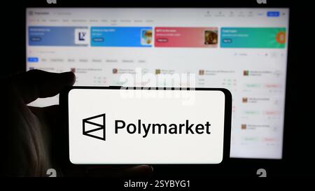 Germany. 27th Nov, 2024. In this photo illustration, a person is holding a cellphone with the logo of crypto prediction market company Polymarket on screen in front of business webpage. (Credit Image: © Timon Schneider/SOPA Images via ZUMA Press Wire) EDITORIAL USAGE ONLY! Not for Commercial USAGE! Stock Photo